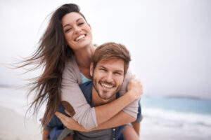 A happy couple smiling and playing outdoors after achieving confidence through plastic surgery procedures.