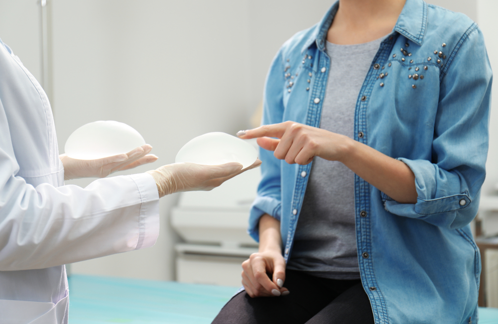 Doctor showing silicone implants to a patient during a consultation for breast augmentation or breast revision surgery, highlighting options in cosmetic breast enhancement procedures.